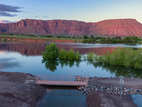 Footbridge overlooking a lake with red rock cliff reflections